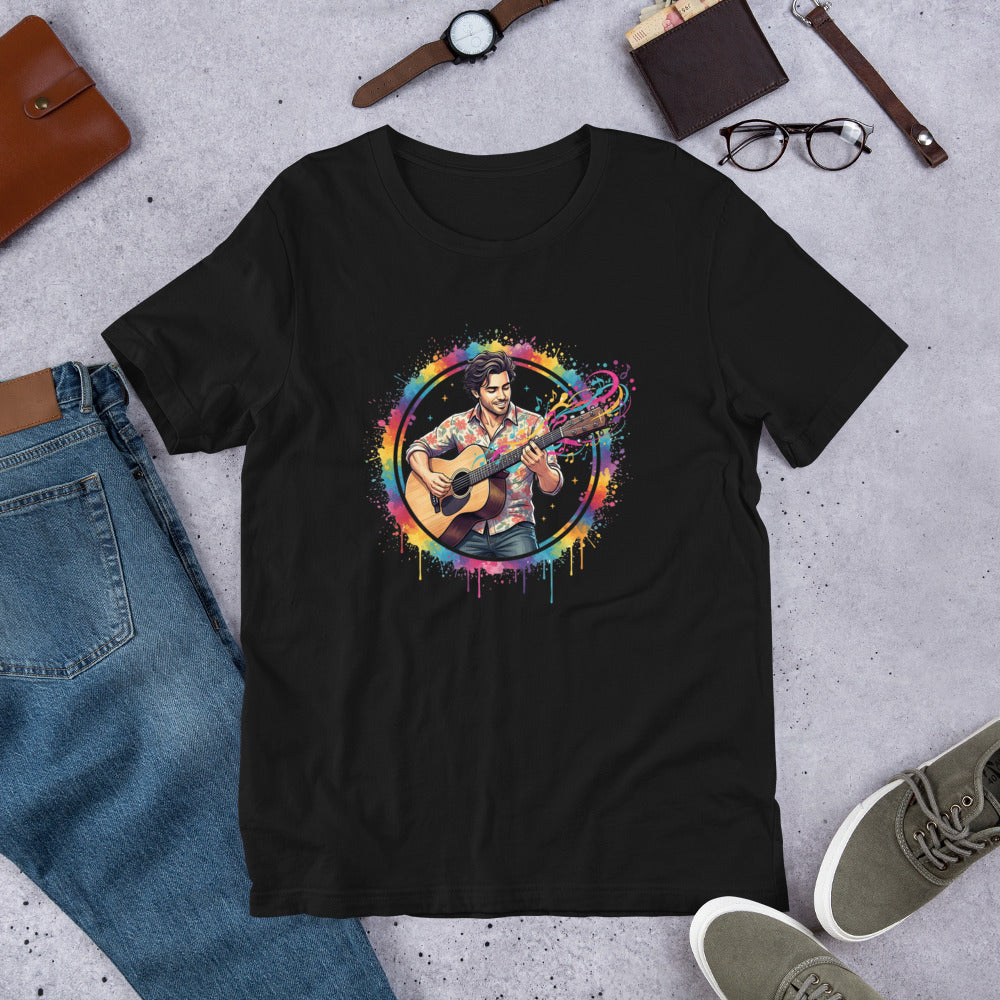Black t-shirt with a colorful graphic of a person playing guitar, surrounded by jeans, shoes, and accessories on a concrete surface.