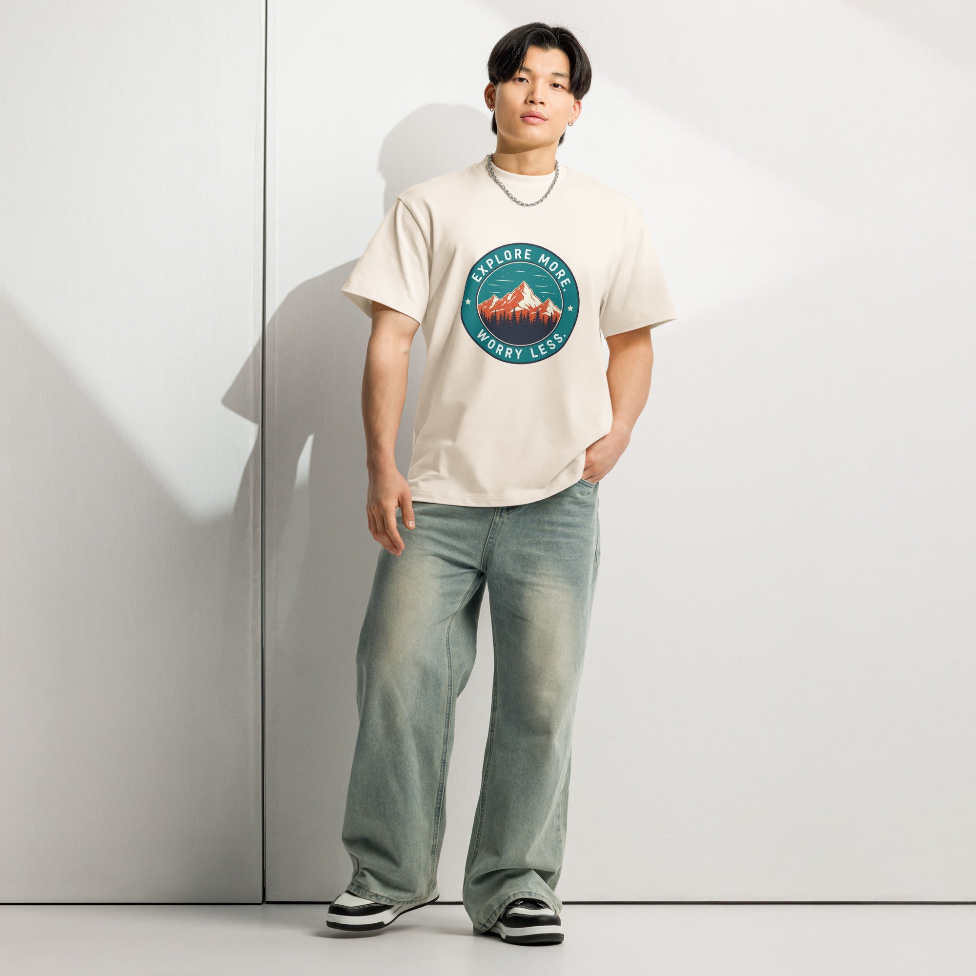Person wearing a white t-shirt with a graphic design and jeans, standing against a plain background