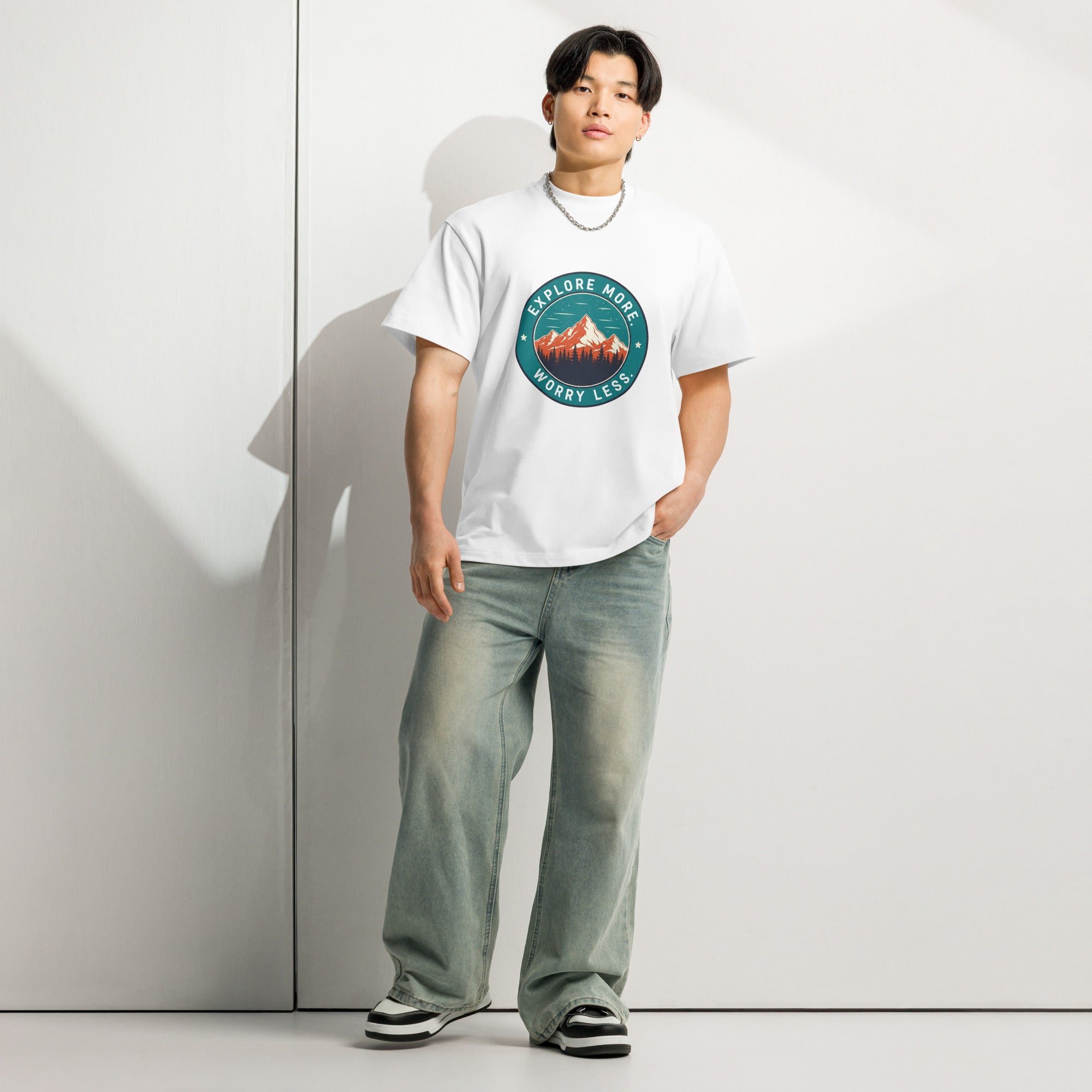 Person wearing a white t-shirt with a mountain graphic and text, standing against a plain background