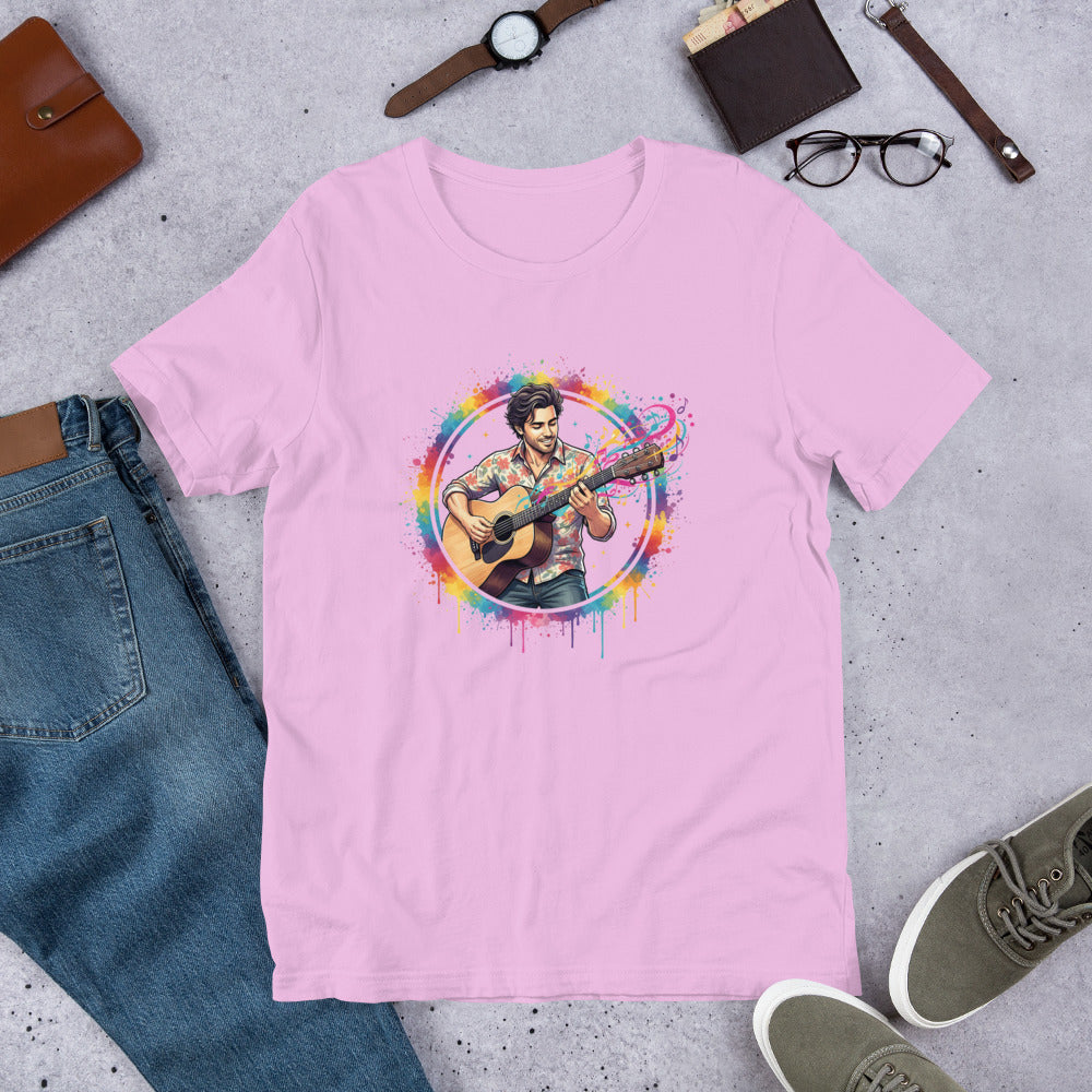 Pink t-shirt with a colorful graphic of a person playing guitar on a gray surface with jeans, shoes, and accessories.