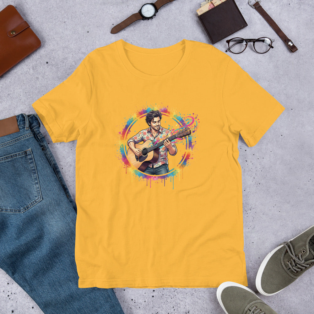 Yellow t-shirt with a colorful graphic of a person playing guitar, placed on a concrete surface with jeans, shoes, and accessories.